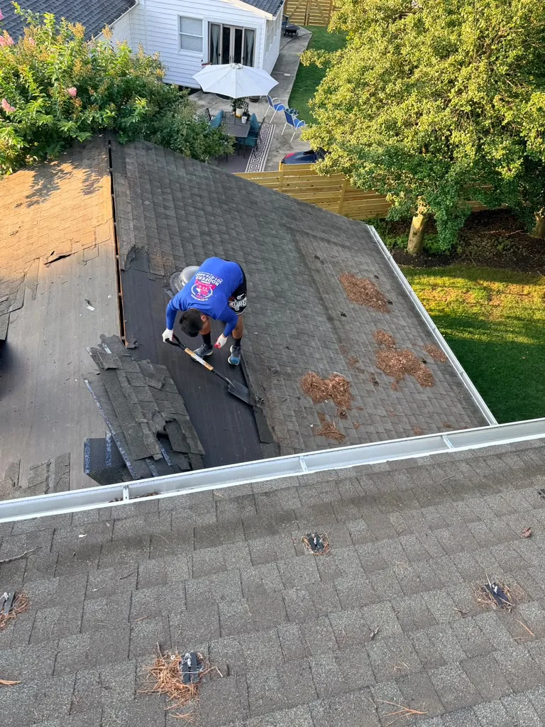 HF Roofing crew member removing old shingles during roof tear-off