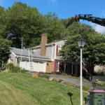 Roof replacement underway with crane delivering materials to the roof